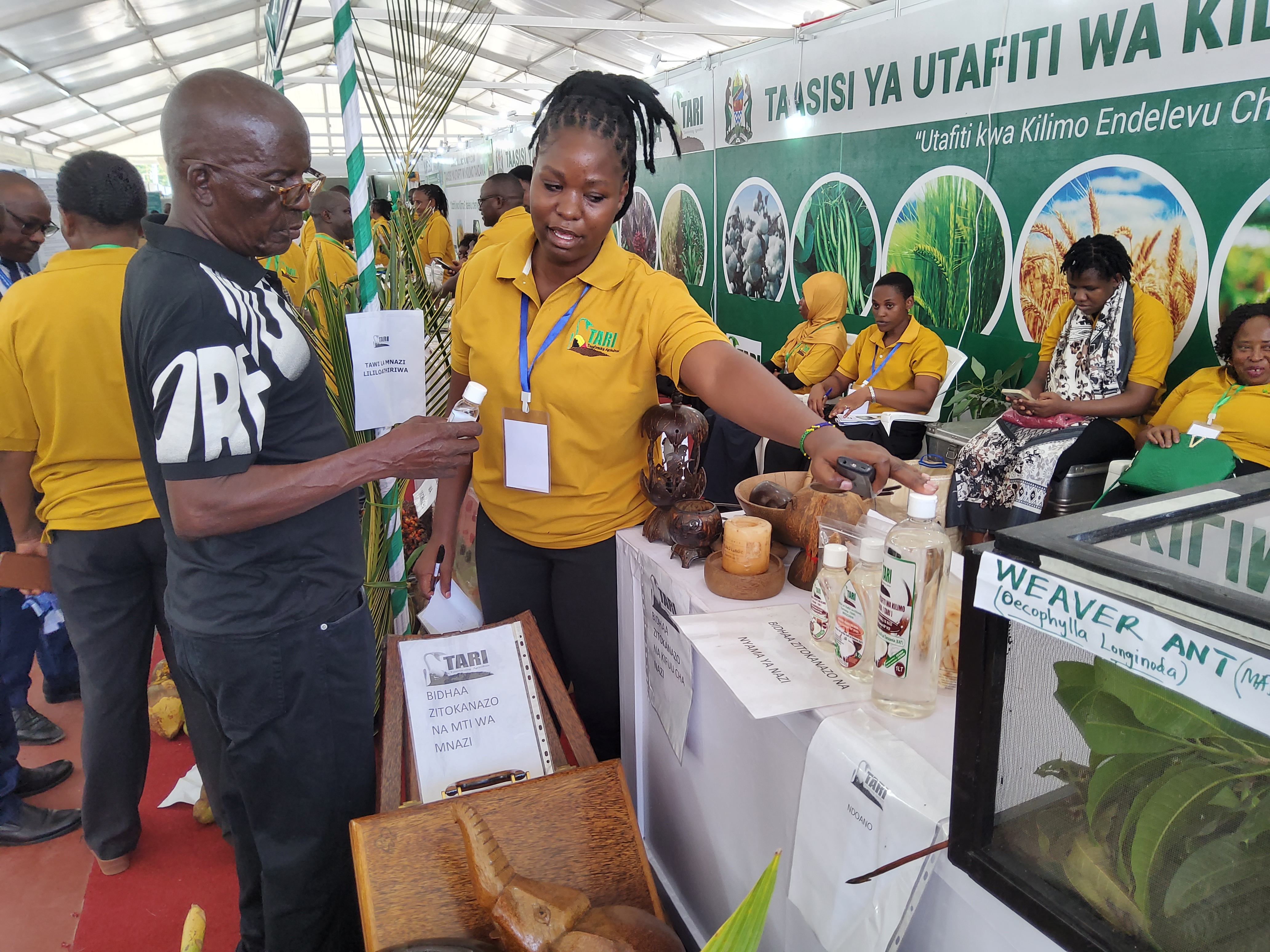 Suzana Theonest (Right), researcher from TARI Mikocheni explaining to a farmer on how to process Virgin Coconut Oil (VCO) and its benefits during Dar es Salaam International Trade Fair (DITF) 2024